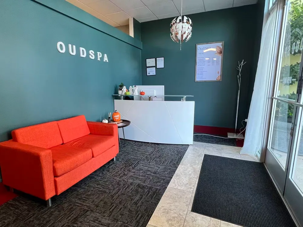 The Oud Spa reception in Brentwood with green walls, a white counter and orange sofa